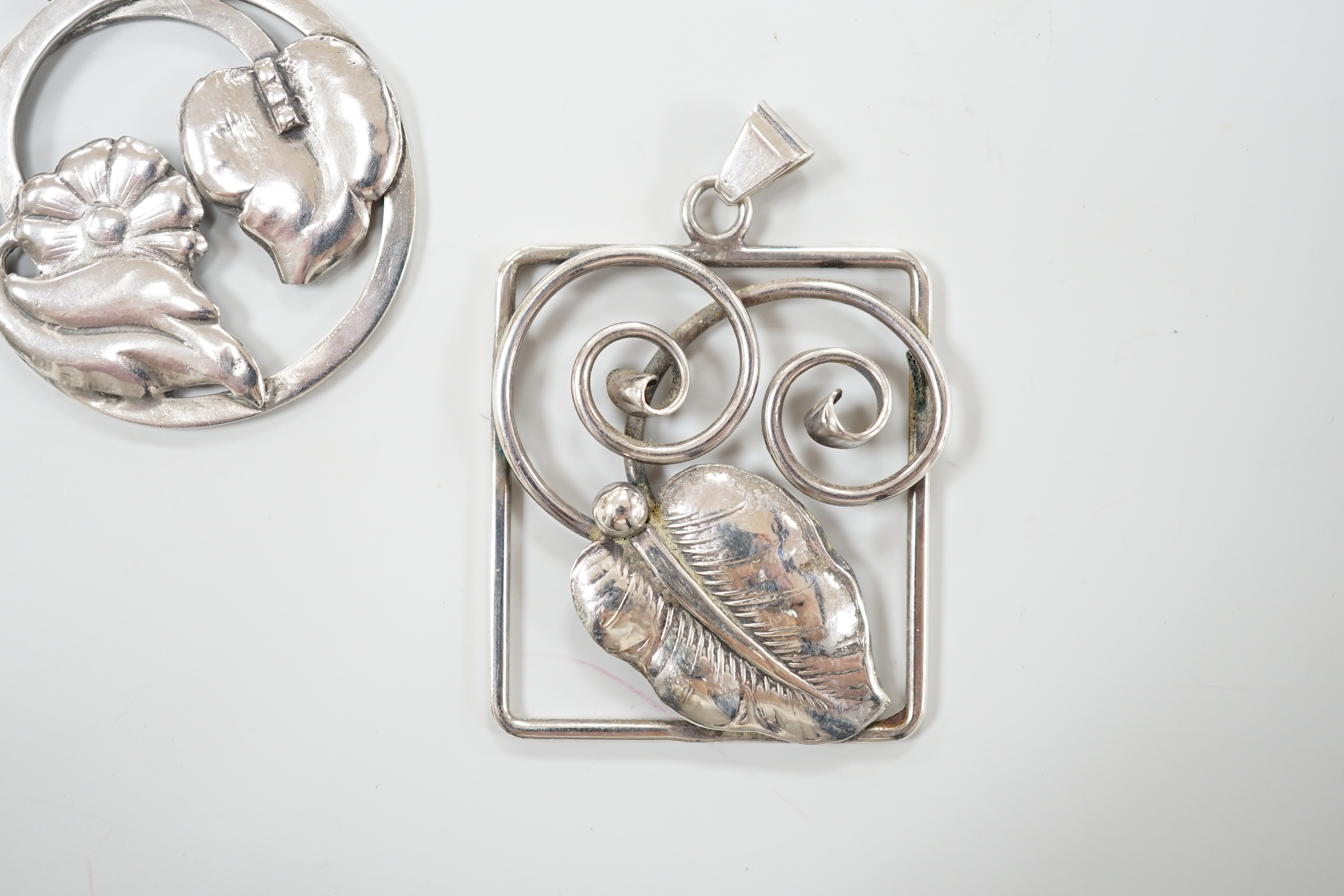 Two 1930's Danish 830 standard white metal pendants, leaf and daisy design, by Bernard Hertz, 4.25cm and leaf and tendril design by Jorgen Christiansen, 4.5cm